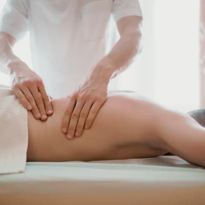A therapist working across a client's back as they lie face down