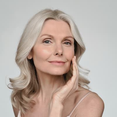 A woman with grey hair resting a hand against her cheek