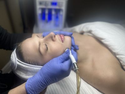 A practitioner guiding a DiamondGlow handpiece across a reclining client’s cheek