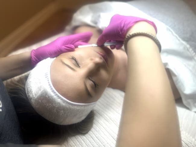 A client resting in a headwrap while a practitioner works across the brow