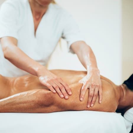 A therapist working along a client’s oiled lower leg during a massage