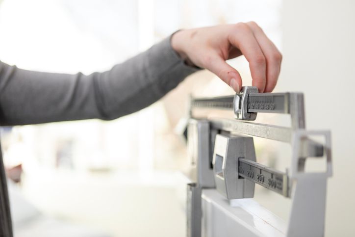 A hand adjusting the counterweight on a balance-beam scale