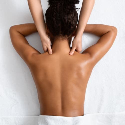 A therapist working across a client's upper back during a massage