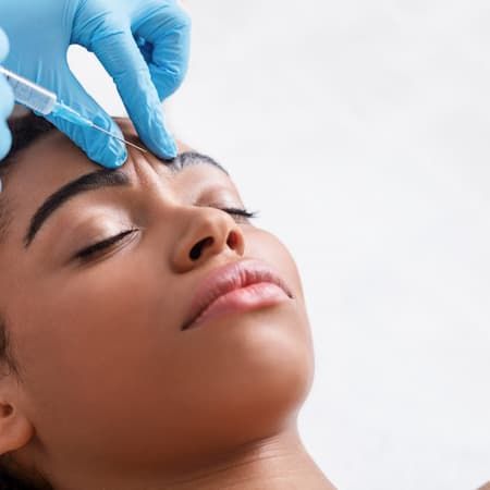 A practitioner injecting a neurotoxin above a reclining client's brow