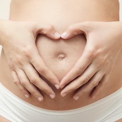 A pregnant woman resting both hands on her abdomen