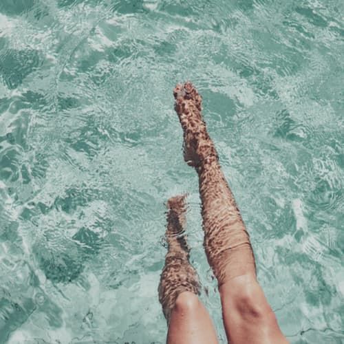 A person's legs at the edge of a pool
